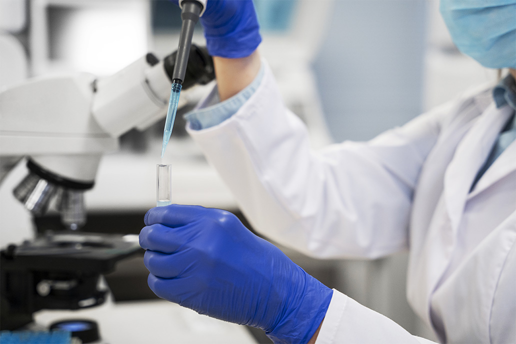 Scientist holding a pipete placing a sample in a test tube